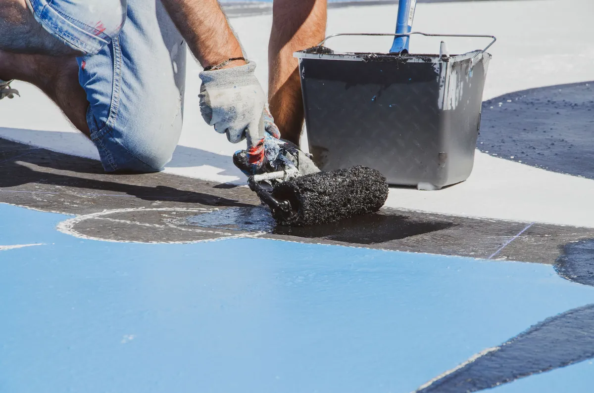 Textured roller applying blue coating to a deck surface