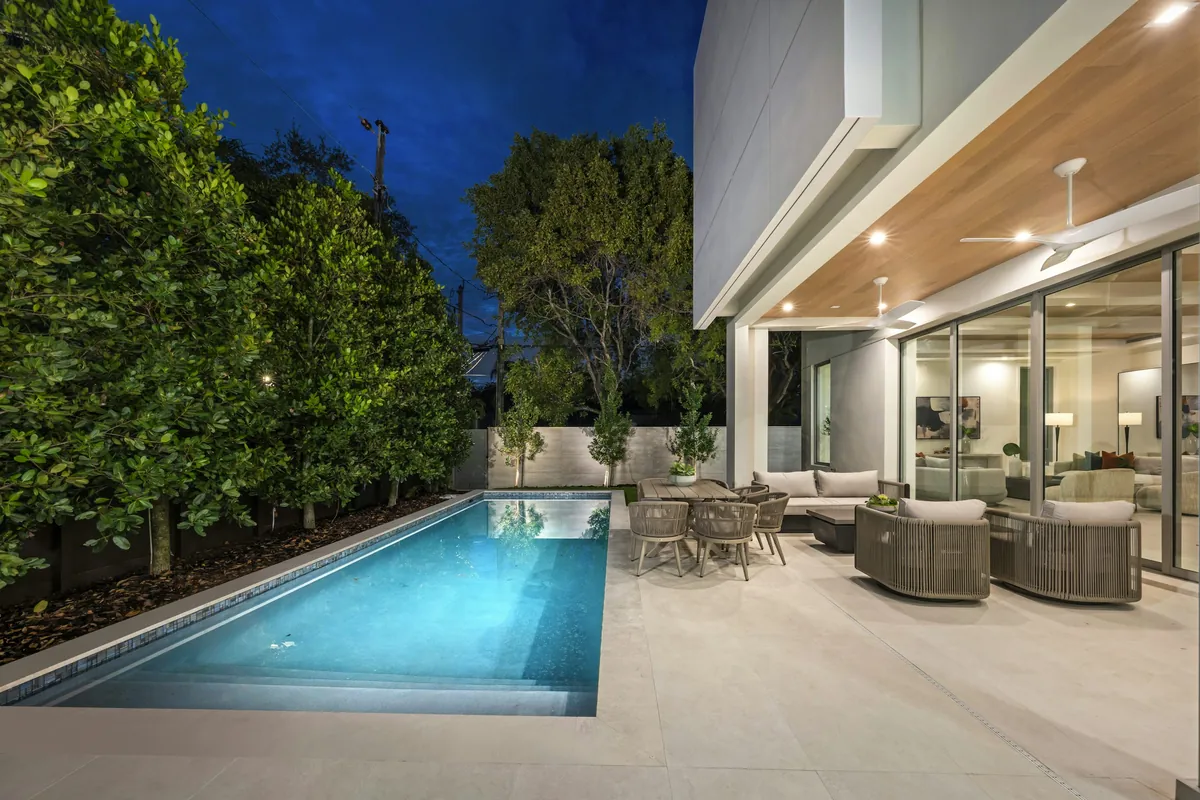 Modern backyard pool with a wide light deck at dusk